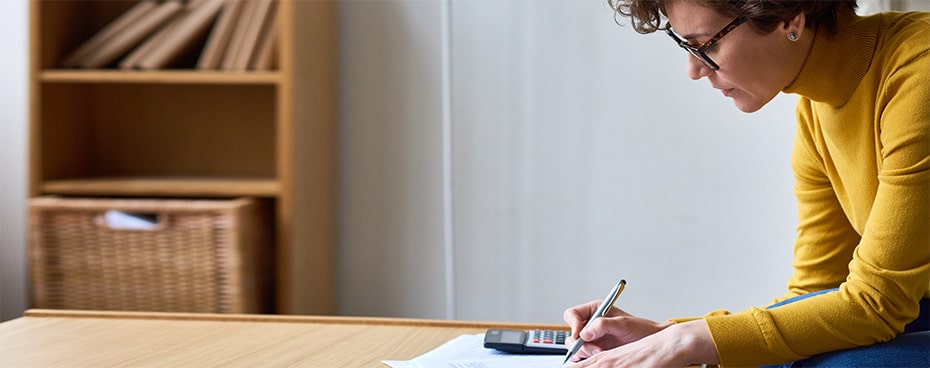 Vrouw met gele trui met pen en rekenmachine